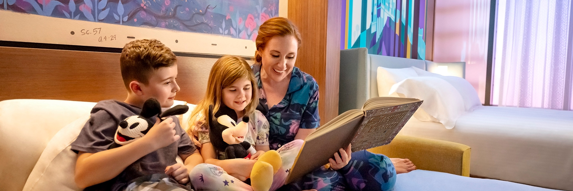 Mother with son and daughter in hotel bed reading a book; Mickey Mouse, Oswald