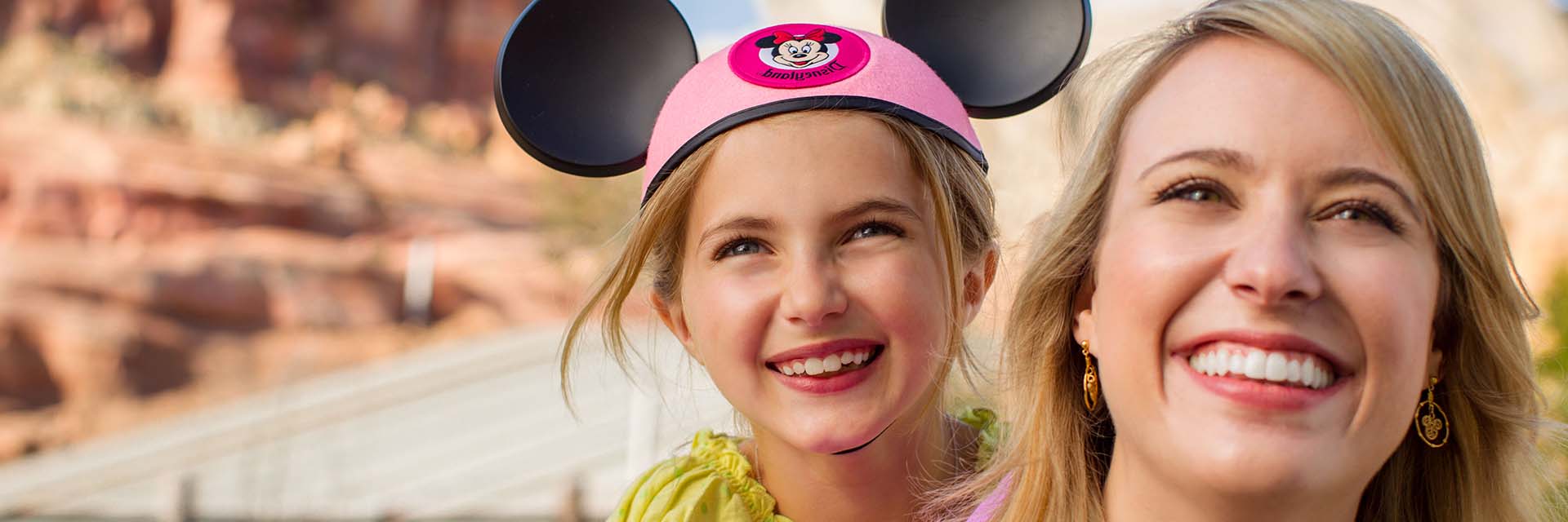 Mom and Daughter in Cars Land; mickey ears; day time; smiling
